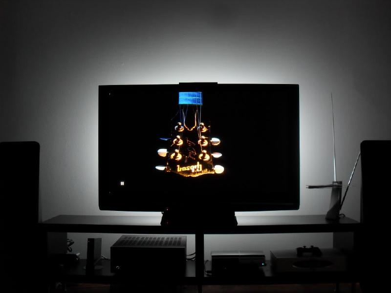 A TV with a soft bias light glowing behind it against the wall