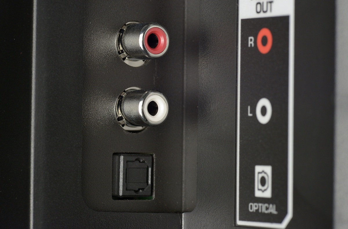 The rear panel of a TV showing both an optical TOSLINK output (square port with cover) and analogue RCA outputs above it