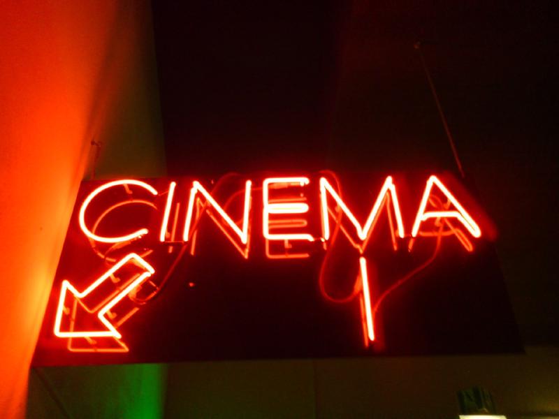 A cinema entrance sign illuminated in the dark