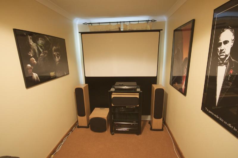 A narrow home theatre room with a smallish projection screen, illustrating how room size constrains screen choice